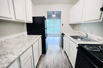 A kitchen with black appliances and white cabinets.